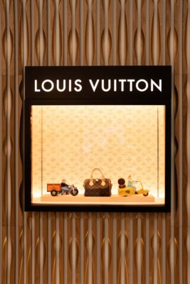 Louis Vuitton storefront display with a black panel reading LVIVITON and a lit glass case showing monogram bags and toy vehicles inside